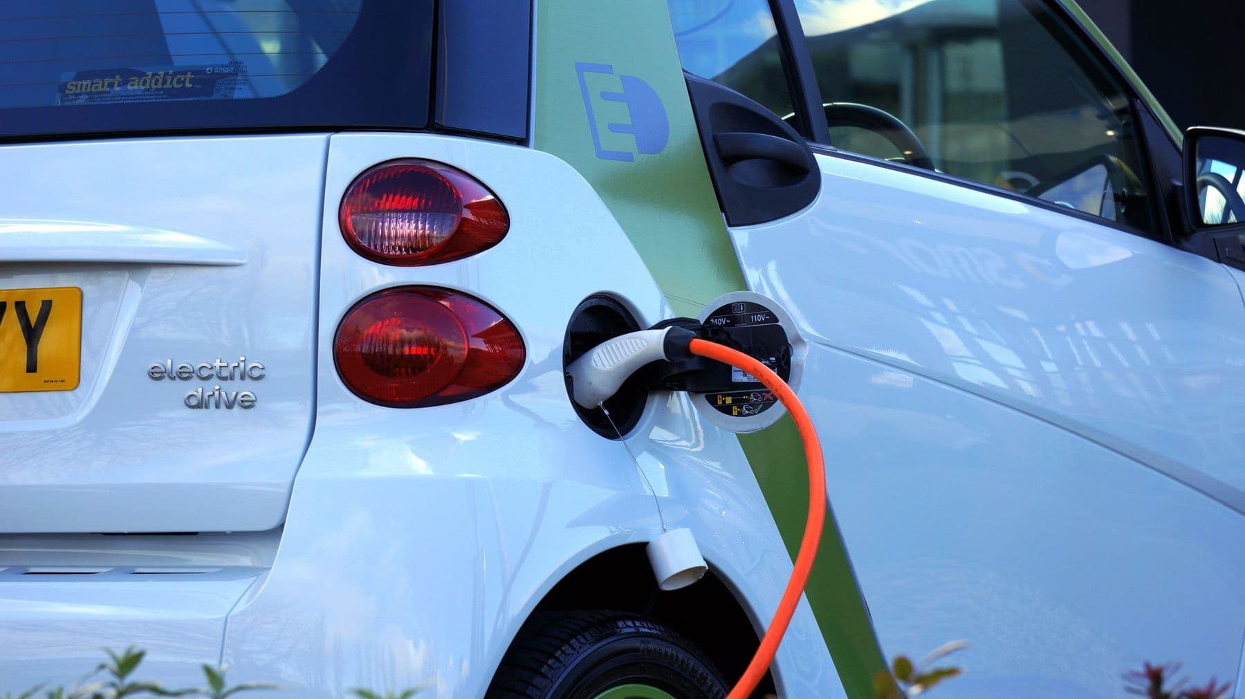 Câble de recharge orange branché sur la trappe d'une voiture électrique